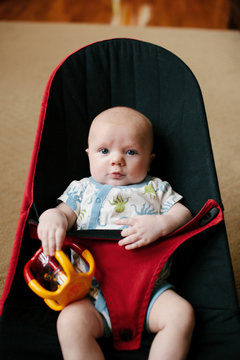 2 month old baby playing in a bouncy seat
