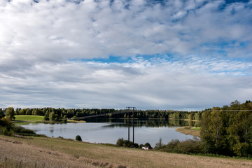 forest reflection in a lake with blue sky and cotton candy clouds in autumn