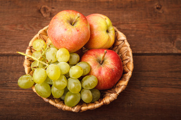 Fresh fruits, apples and a grape basket on a wooden background. Background. Autumn, harvest. Thanksgiving Day. Space for text.