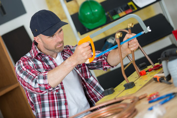 plumber sawing an iron pipe