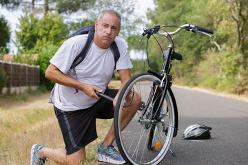 Obraz premium portrait of handsome man pumping bicycle tires at park