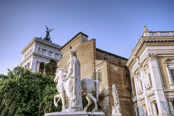 Obraz premium Marble statues of the Dioscuri, Castor and Pollux, at the top of the staircase, in Capitol Square or Piazza del Campidoglio, Rome, Italy. Basilica of Santa Maria in Aracoeli in background