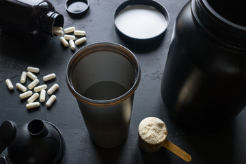 shaker, protein, creatine and other sports supplements on a black background