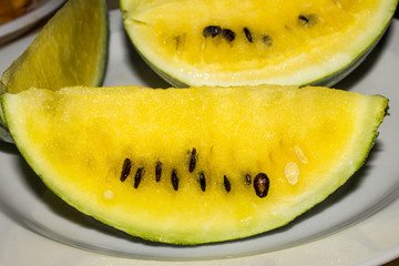 A slice of a yellow watermelon lies on a plate