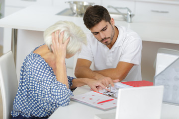 photo of young man helping his grandmother managing her money