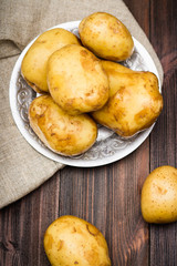 Raw potatoes on a brown wooden background