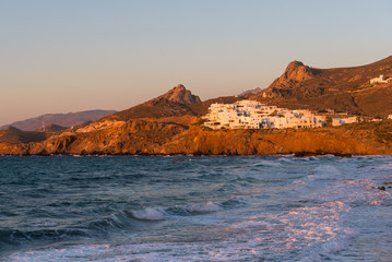 Fototapeta na wymiar White houses situated on the hill in sunset light. A view from promenade in Naxos town. Cyclades, Greece. 