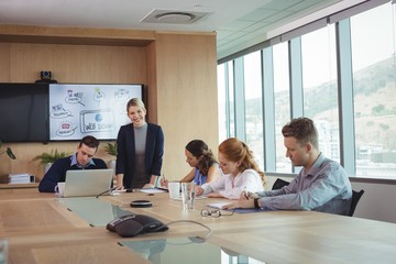 Smiling businesswoman with team working at conference table