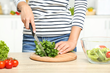 Young woman cutting parsley in the kitchen