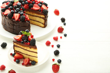 Piece of chocolate cake with berries in plate on wooden table