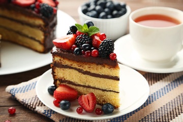 Piece of chocolate cake with berries in plate on wooden table