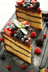Pieces of chocolate cake with berries on cutting board