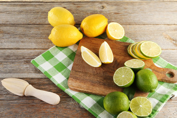 Ripe limes and lemons on cutting board with wooden juicer