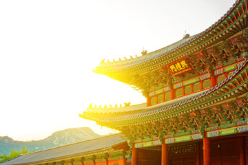 Fototapeta na wymiar Sun behind roof top of the gate to Gyeongbokgung Palace - translation for this word is 