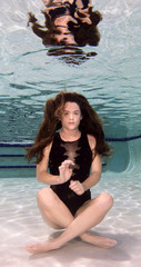 A woman wearing a black swimsuit underwater.