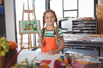 Portrait of happy girl holding paintbrushes