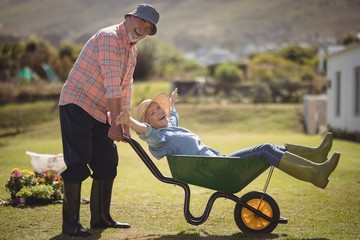 Senior man giving woman ride in wheelbarrow