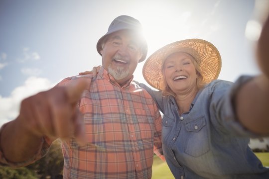 Smiling senior couple standing in lawn on a sunny day