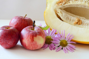 apples and cut the melon next to the flowers Aster on a white background