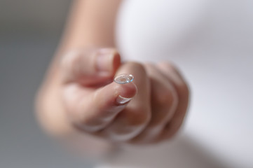 Young woman with contact lens on her finger.