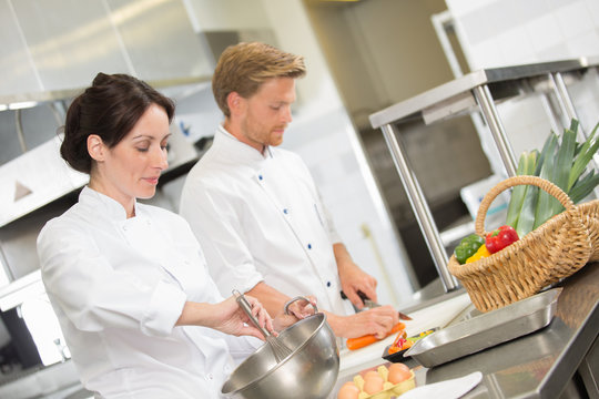 positive professional chef and cook working at restaurant kitchen