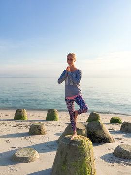 Eine Frau macht Yoga auf den Tetrapoden am Strand von Sylt