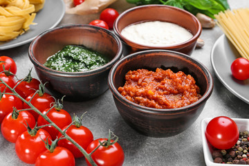 Delicious pesto, bolognese and white sauces for pasta in bowls on table