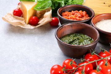 Delicious pesto, bolognese and white sauces for pasta in bowls on table