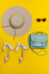 Fashionable concept. Women's beach hat, handbag, white shoes. Yellow background, top view