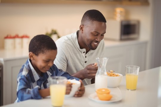 Father and son having breakfast in kitchen