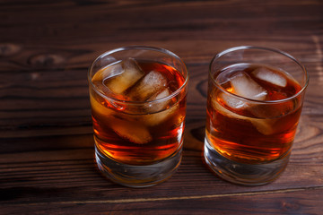 Whiskey with ice cubes on wooden table, copy space.  Alcohol drinks, bar concept