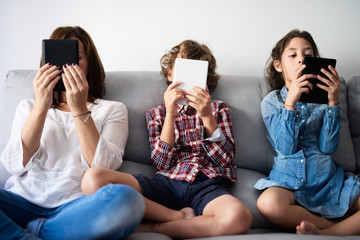 Family reading on sofa via tablets