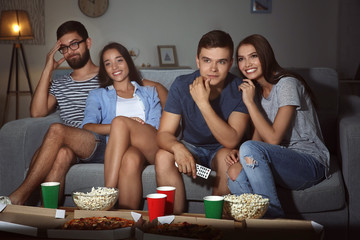 Friends watching TV in evening at home