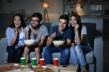 Friends watching TV in evening at home