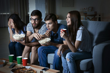 Friends watching TV in evening at home