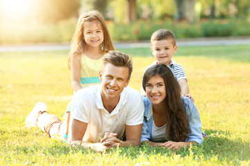 Fototapeta premium Happy family lying on grass in park