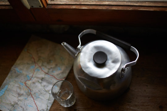 Old aluminum kettle with glass and map seen from above