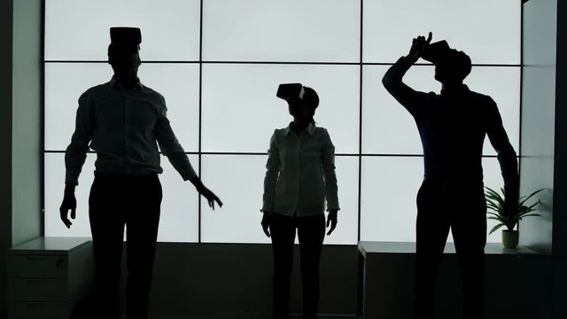  Business team in silhouette trying out virtual reality viewers on white background