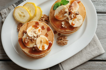 Plate with yummy banana pancakes on wooden table
