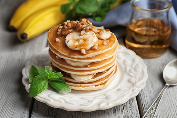 Plate with yummy banana pancakes on wooden table