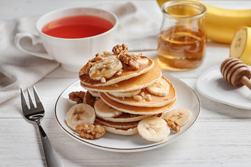 Plate with yummy banana pancakes on wooden table