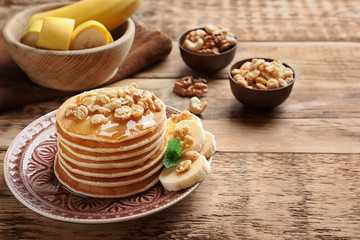 Obraz na płótnie Canvas Plate with yummy banana pancakes on wooden table