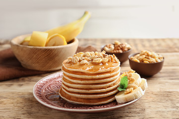 Plate with yummy banana pancakes on wooden table