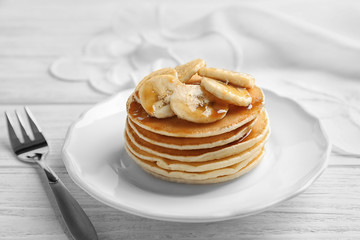 Fototapeta na wymiar Plate with yummy banana pancakes on wooden table