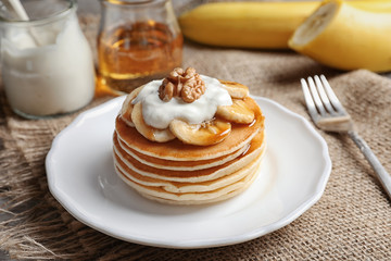 Plate with yummy banana pancakes on kitchen table