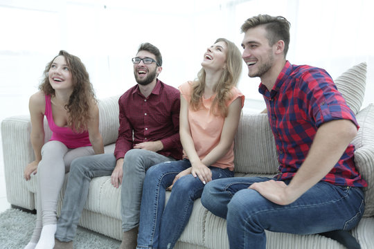 group of smiling young people sitting on the couch
