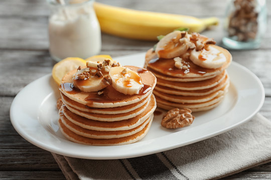 Plate with yummy banana pancakes on wooden table