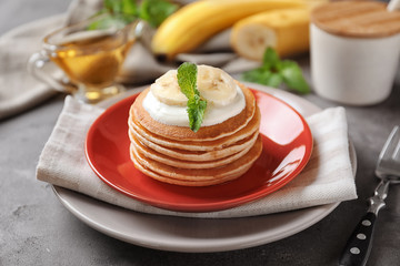 Obraz na płótnie Canvas Plate with yummy banana pancakes on kitchen table