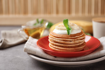 Plate with yummy banana pancakes on kitchen table