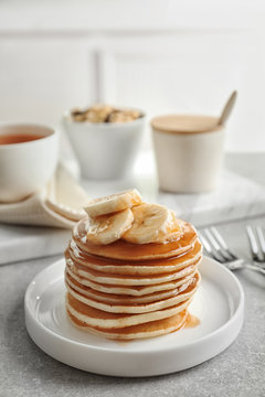 Plate with yummy banana pancakes on kitchen table